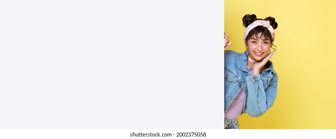 Smiling happy cute Asian girl hiding behind a blank white board isolated on yellow background. - Powered by Shutterstock