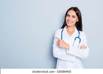Smiling happy doctor pointing with finger on blue background