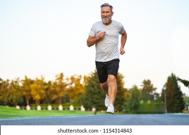 The Smiling Happy Elderly Man Running On The Road