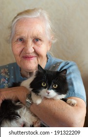 Smiling happy elderly woman with her cat. Selective focus on a cat