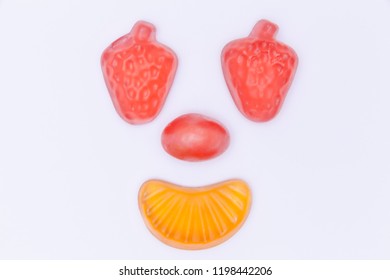 A Smiling Happy Face Created With Hard And Soft Sugar Candy: Strawberry Eyes, Tangerine Mouth. Isolated Studio Shot.
