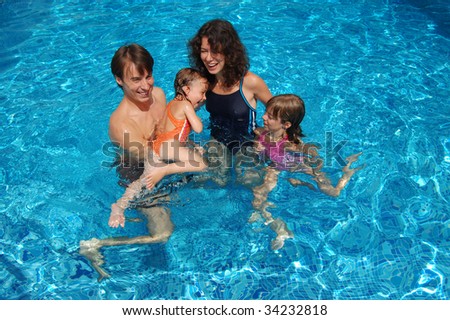 Smiling happy family with kids having fun in swimming pool