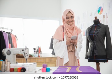 smiling happy fashion designer using mobile phone in her office - Powered by Shutterstock