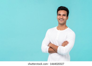 Smiling Happy Indian Man With Arms Crossed In Plain White T-shirt Isolated On Light Blue Background