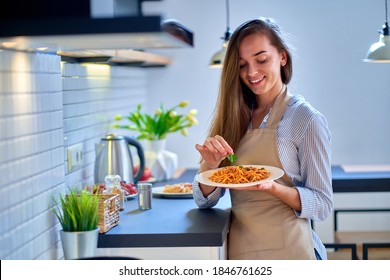 Smiling happy joyful cute cooking woman wearing apron decorates a fresh food with parsley leaf for dinner                                      - Powered by Shutterstock