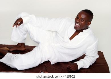 Smiling Happy Man Wearing An All White Attire In A Casual Reclining Pose.