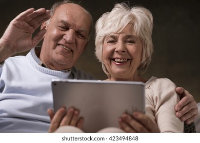 Smiling Happy Married Older Couple Watching Movies Online On New Tablet In The Evening At Home