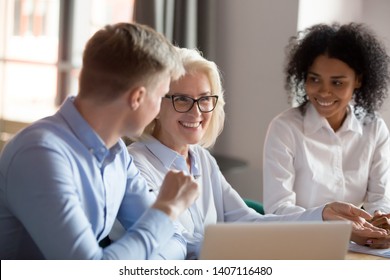 Smiling happy mature older female mentor coach boss executive talking at diverse group meeting having fun business conversation joke laughing with colleagues at corporate team briefing conference