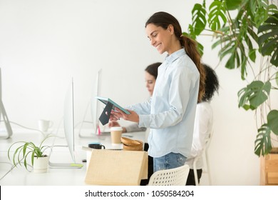 Smiling Happy New Employee Or Intern Unpacking Box With Belongings At Workplace Holding Framed Picture, Hired Manager Settling In Office On Desk, Newcomer Team Member On First Day At Work Concept