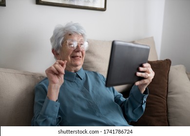 Smiling happy senior Caucasian woman sitting in her living room and making a video call on a tablet - Shutterstock ID 1741786724