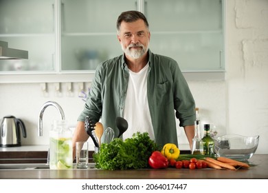 Lächeln glückliche Senioren Mann stehen in der Küche Tisch, Blick auf Kamera, bereiten gesunde Lebensmittel, machen frische Gemüsesalat genießen Kochen allein zu Hause, Porträt.