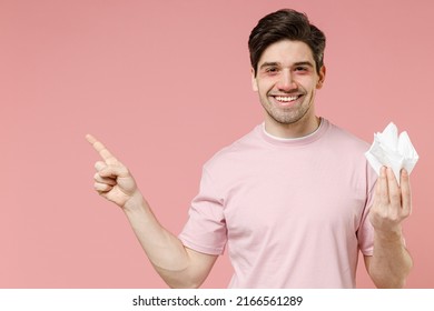 Smiling Happy Sick Ill Allergic Man Has Red Eyes Runny Nose Suffer From Allergy Hold Paper Napkin Pointing Finger Aside On Workspace Promo Advert Area Isolated On Pastel Pink Color Background Studio