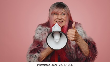 Smiling Happy Stylish Old Woman Talking With Megaphone, Proclaiming News, Loudly Announcing Sale Advertisement, Warning Using Loudspeaker To Shout Speech. Senior Elderly Grandmother On Pink Background