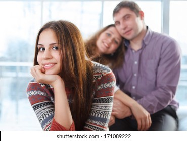Smiling happy teenage girl sitting in front of her parents