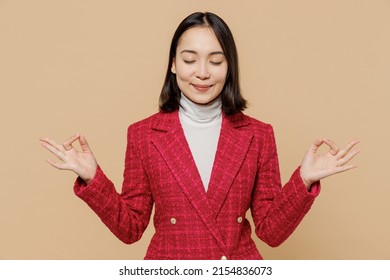 Smiling happy woman of Asian ethnicity in red jacket hold spread hands in yoga om aum gesture relax meditate try to calm down isolated on plain pastel beige background studio. People lifestyle concept