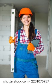smiling happy woman builder holding level and tablet, ready to check project in new building. women's work in men's professions and equality - Shutterstock ID 2231075957