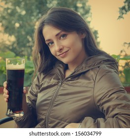 Smiling Happy Woman Drinking Dark Beer On Terrace Cafe. Closeup Vintage Portrait 