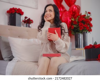 Smiling happy woman with gift box talking on phone with loved, one sitting in bed and looking at camera. Celebration of valentine's day, wedding and love day, women's day. morning love bedroom.