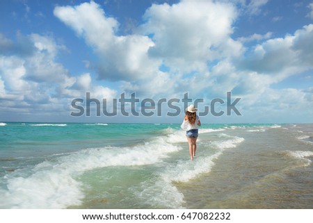 Smiling, happy, woman walking and relaxing on the beach at sunrise, beautiful cloudy sky reflected on the beach, South Beach, Miami , Florida, USA.