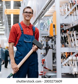 Smiling Hardware Store Clerk With A Large Sledgehammer Standing In The Sales Floor.