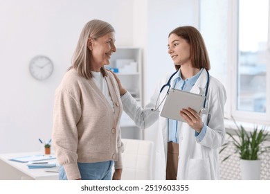 Smiling healthcare worker with tablet supporting senior patient in hospital - Powered by Shutterstock