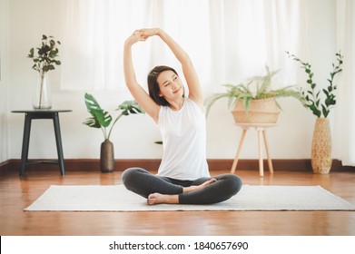 Smiling Healthy Asian Woman Doing Yoga Shoulder Stretching At Home In Living Room