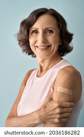 Smiling healthy mature older senior happy woman showing bandage on arm after getting vaccination. Vaccine and old people inoculation, elderly immunity for covid prevention concept. Vertical portrait
