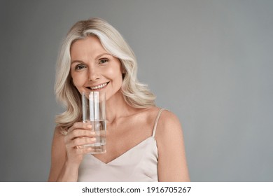 Smiling Healthy Thirsty Fit Mid Aged 50s Woman Holding Glass Drinking Water. Happy Mature Lady Hydrating Body With Clean Filtered Fresh Mineral Water For Skin Care, Beauty, Diet Nutrition Hydration.