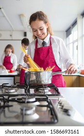 Smiling High School Student Cooking Pasta In Home Economics Class