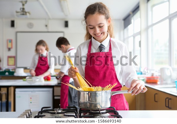 Smiling high school student cooking pasta in home\
economics class