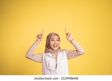 Smiling hijab woman with finger pointing up hand gesture - Powered by Shutterstock