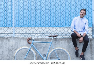 Smiling hipster boy sitting on urban ledge - Powered by Shutterstock