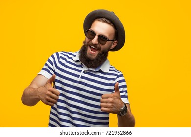 Smiling hipster man in hat and sunglasses gesturing thumbs up.  - Shutterstock ID 721952866
