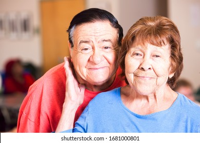 Smiling Hispanic Couple Laughing  In A Busy Senior Center
