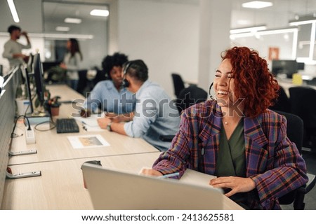 Smiling hispanic customer services agent woman with headset working in an office. Portrait of a a latino female agent working on a laptop in a call center and talking with clients and customers.