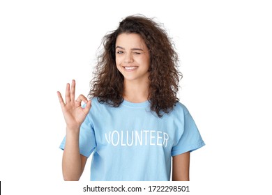 Smiling Hispanic Teen Girl, Young Latin Woman Activist Volunteer Showing Ok Hand Sign Looking At Camera Isolated On White Studio Background. Volunteering Charity Helping Services Concept. Portrait.