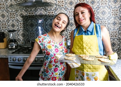Smiling hispanic teenage girl with cerebral palsy in the kitchen baking cookies with her mother in Latin America disability concept