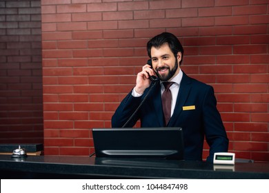 Smiling Hotel Receptionist Taking Phone Call At Workplace