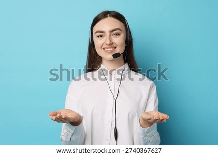 Smiling hotline operator in headset on light blue background