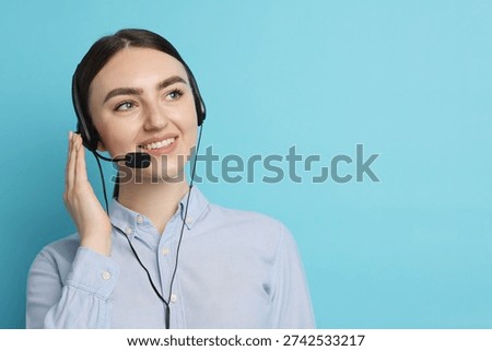 Smiling hotline operator in headset on light blue background. Space for text