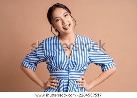 smiling humor tongue out happiness playful asia woman adult wear well dress blue stripe color pattern portrait studio shot,confident cheerful freshness smiling asian woman positive emotion look camera