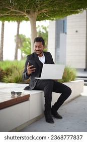 Smiling indian business man working on laptop at park. Young indian student or remote teacher using computer remote studying, virtual training, watching online education webinar - Shutterstock ID 2368777837