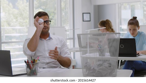 Smiling Indian Businessman Throwing Paper Ball In Trash Basket On Desk In Office. Portrait Of Happy Young Male Employee Having Fun Throw Paper Ball In Waste Bin