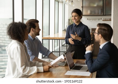 Smiling Indian businesswoman leading corporate meeting with diverse colleagues, coach mentor training employees, discussing project strategy, sharing ideas, business partners negotiation concept - Shutterstock ID 1931169122