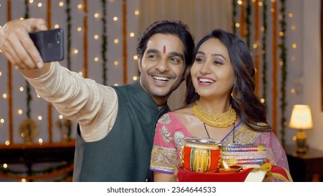 Smiling Indian couple taking selfie after Karwa Chauth celebrations - capturing memories. Newly wed couple capturing pictures after celebrating Karwa Chauth festival - dressed beautifully in tradit... - Powered by Shutterstock