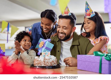 Smiling indian father blow out candle on the cake for his birthday with wife and two children. Cute daughter and little son organized a surprise party for dad birthday with mother at home. - Powered by Shutterstock