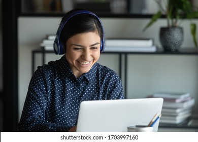 Smiling Indian female employee in wireless headset consult client on laptop online, happy ethnic woman worker in headphones talk on video call with customer or colleague, WebCam conference concept - Shutterstock ID 1703997160