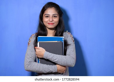 Smiling Indian Female Student Holding Books And File , College Or School Student And Education Concept Isolated On Blue Background With Copy Space.