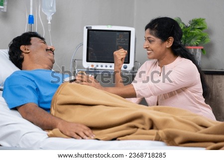 Smiling Indian middle aged wife or women giving confidence to sick admitted patient or husband at hospital - concept hope, encouragement and positive emotion