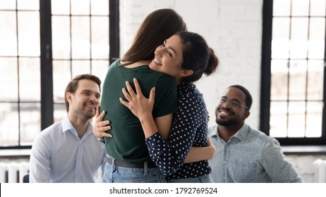 Smiling Indian psychologist hugging patient at group counselling session, giving psychological help, expressing support and empathy, helping overcome problems, depressing or addictions treatment